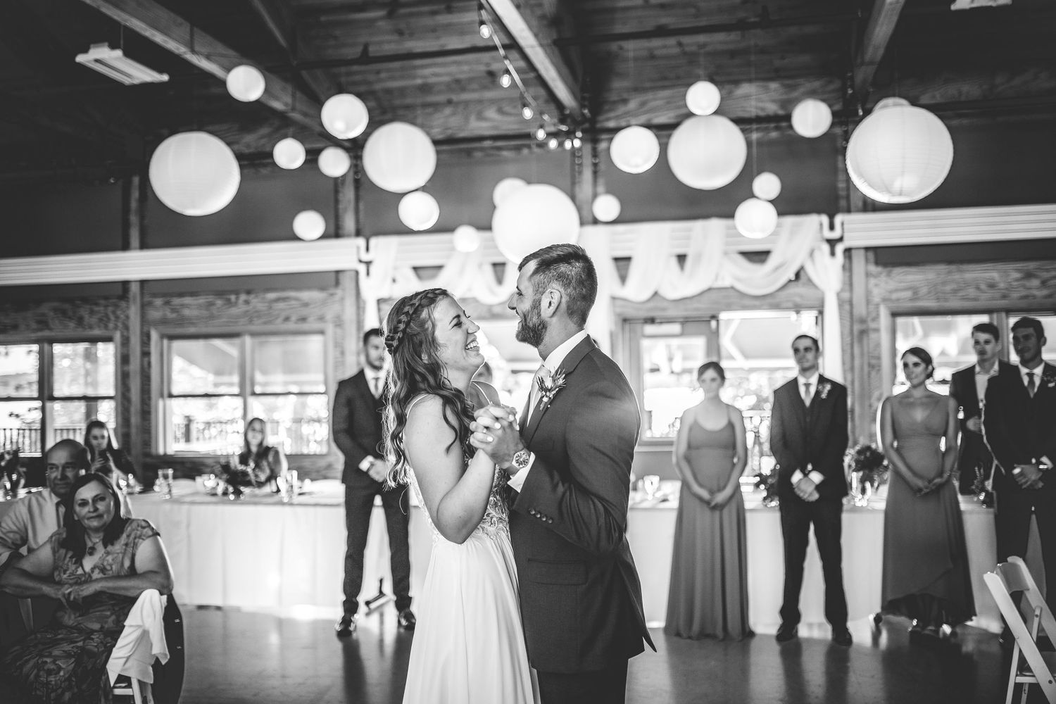 Black and white photo of a wedding reception space with glowing paper lanterns creating ambient lighting.