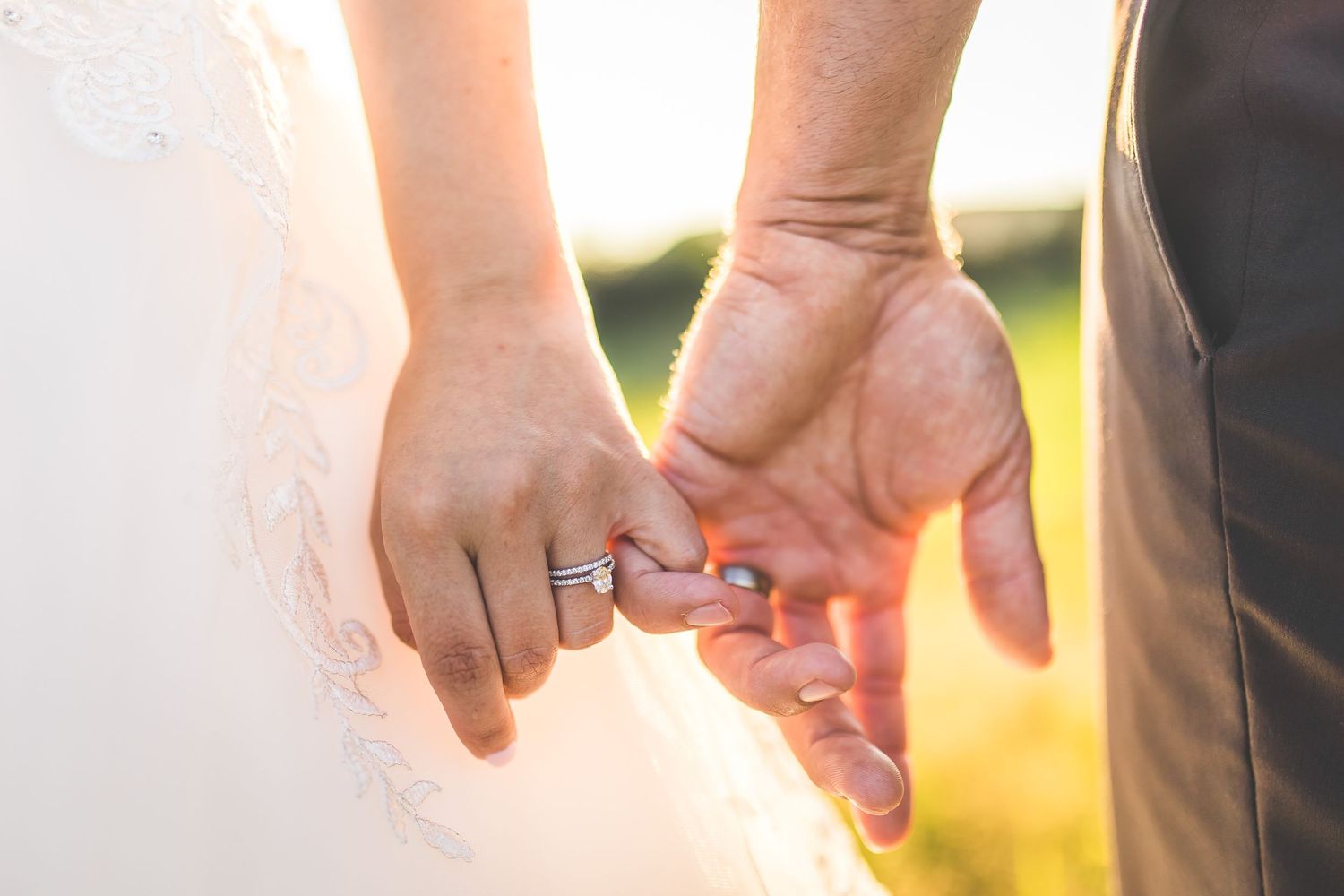 Close-up of hands holding sparklers during a wedding celebration at sunset.