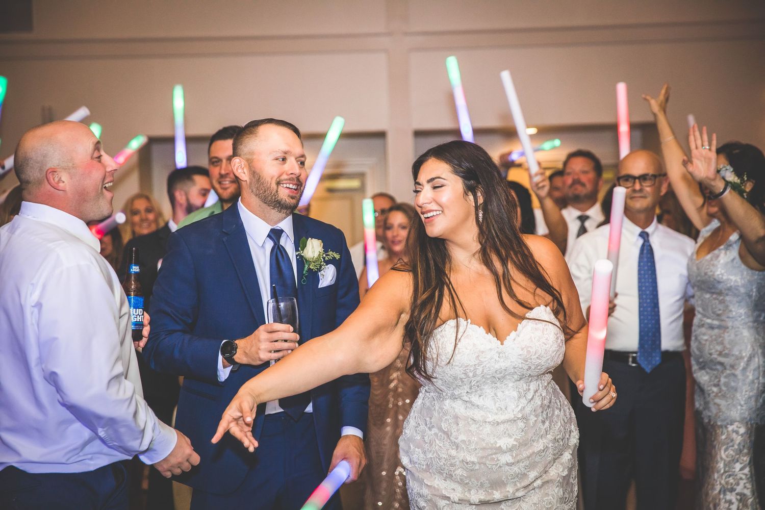 Wedding reception guests dance and celebrate with glowing LED light sticks on a lively dance floor.