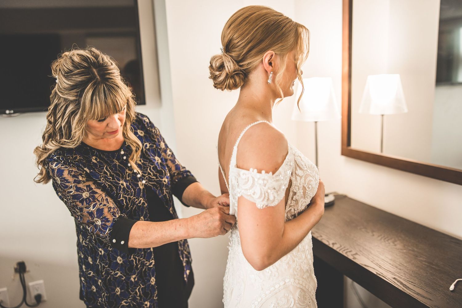 Wedding preparation scene with bride getting ready in white dress.