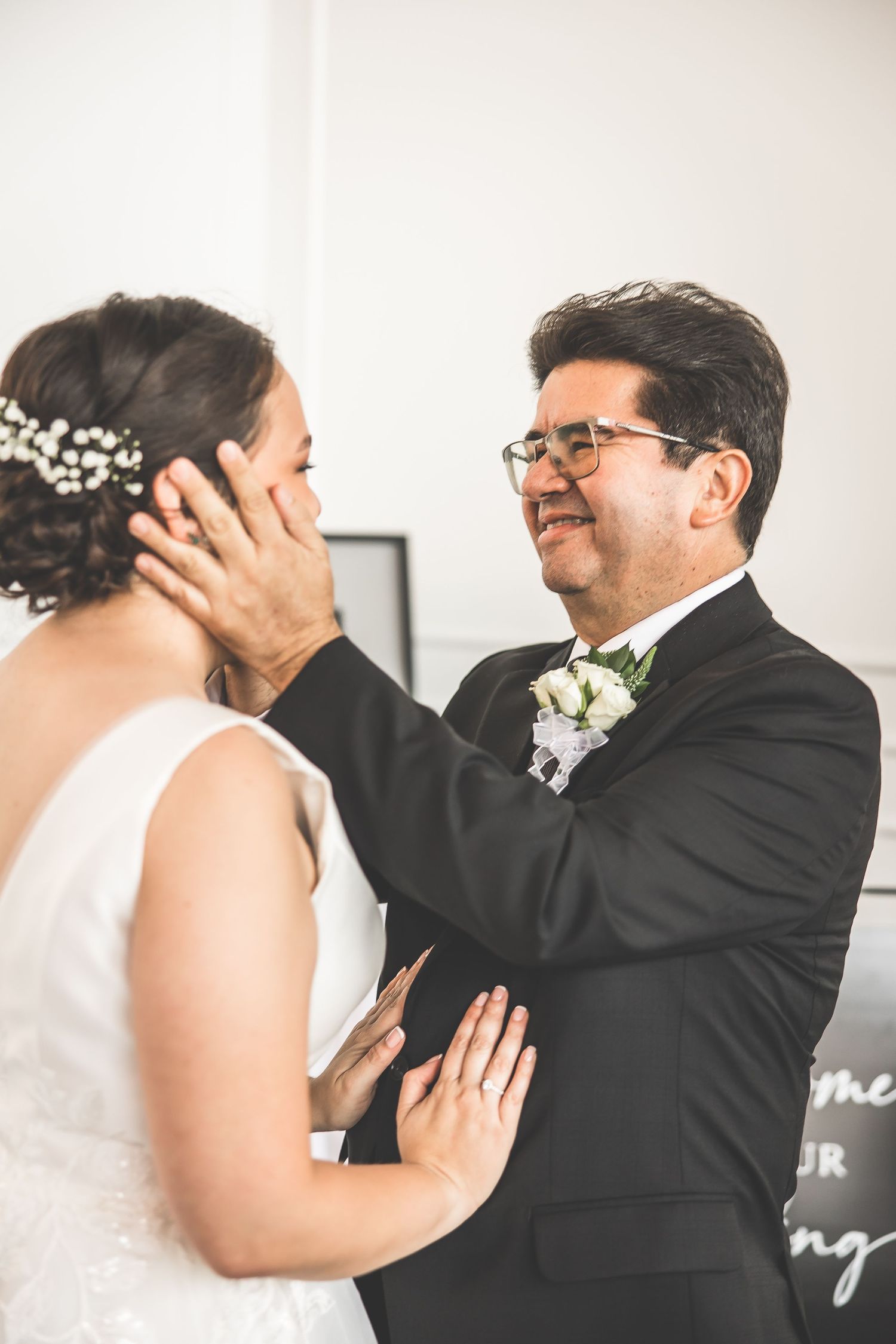 Intimate wedding portraits captured against a clean white wall background.