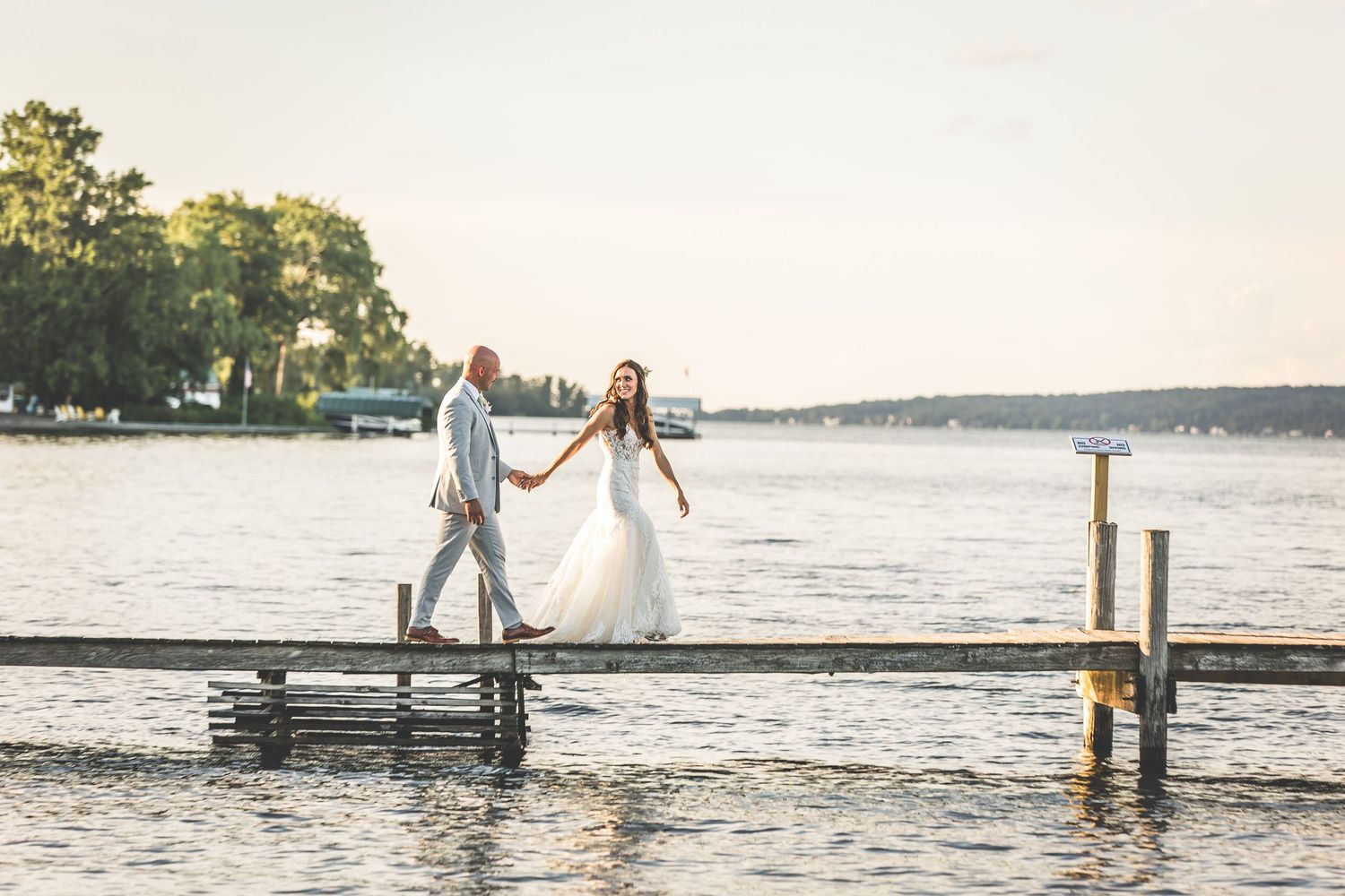 Scenic waterfront wedding portraits with dock and lake views at sunset.