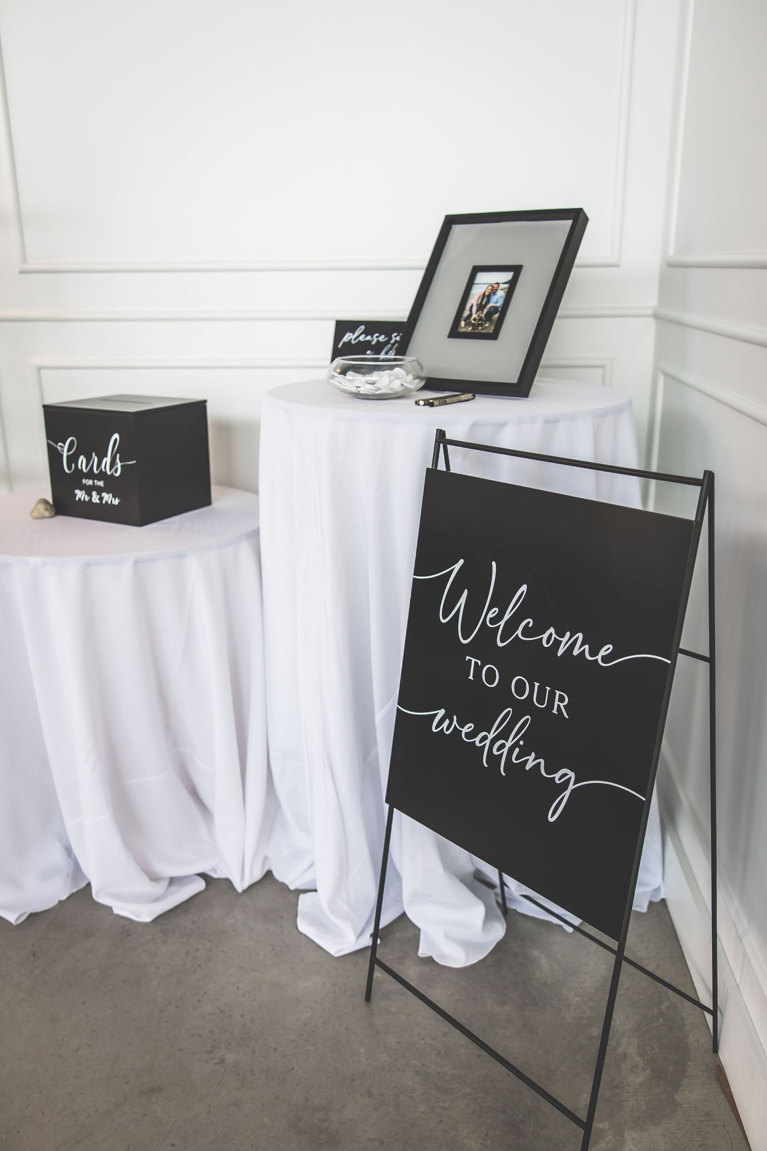 Black and white wedding welcome signs displayed on metal stands with elegant script lettering.