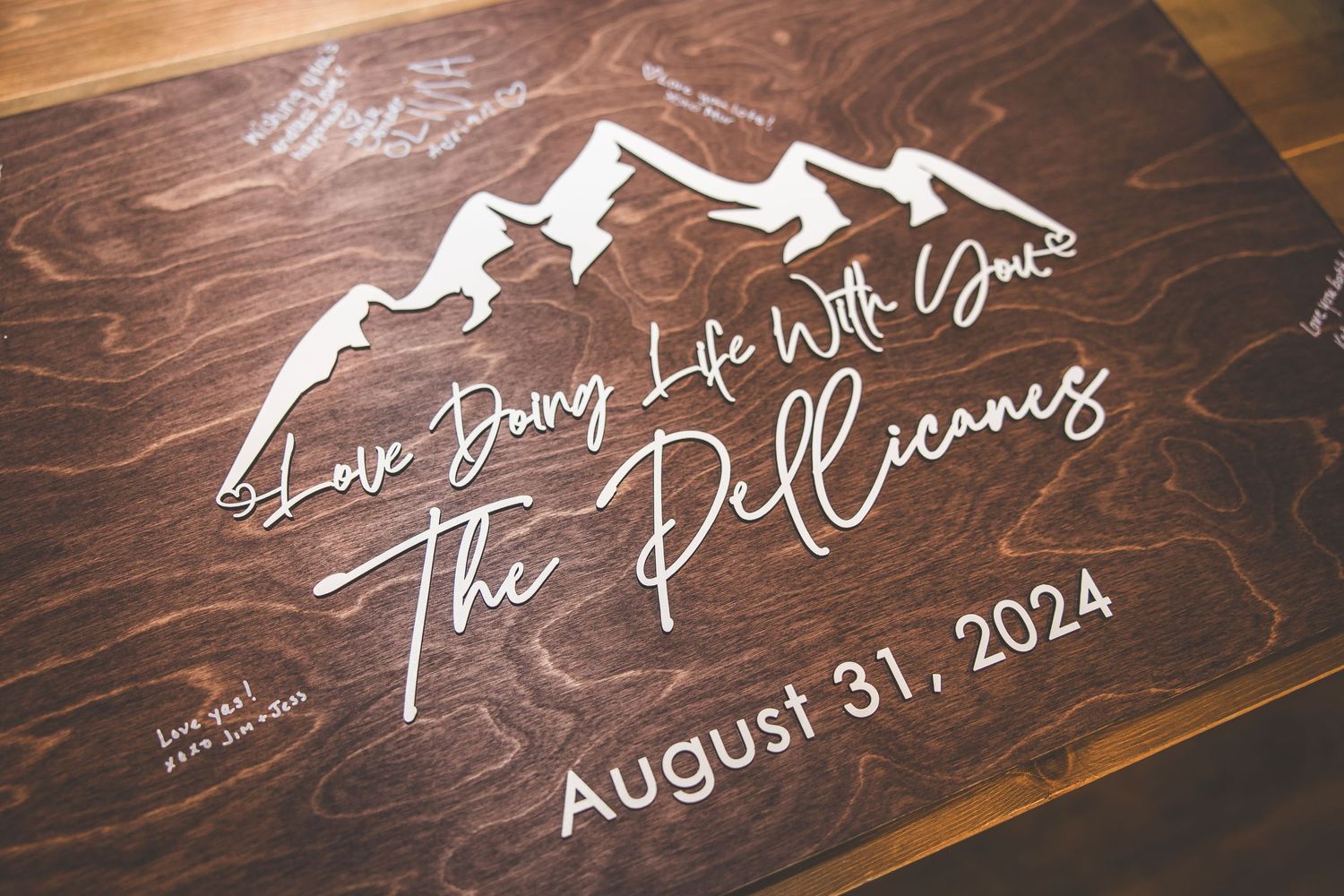 Wooden sign with white mountain design and wedding date displayed in elegant script.