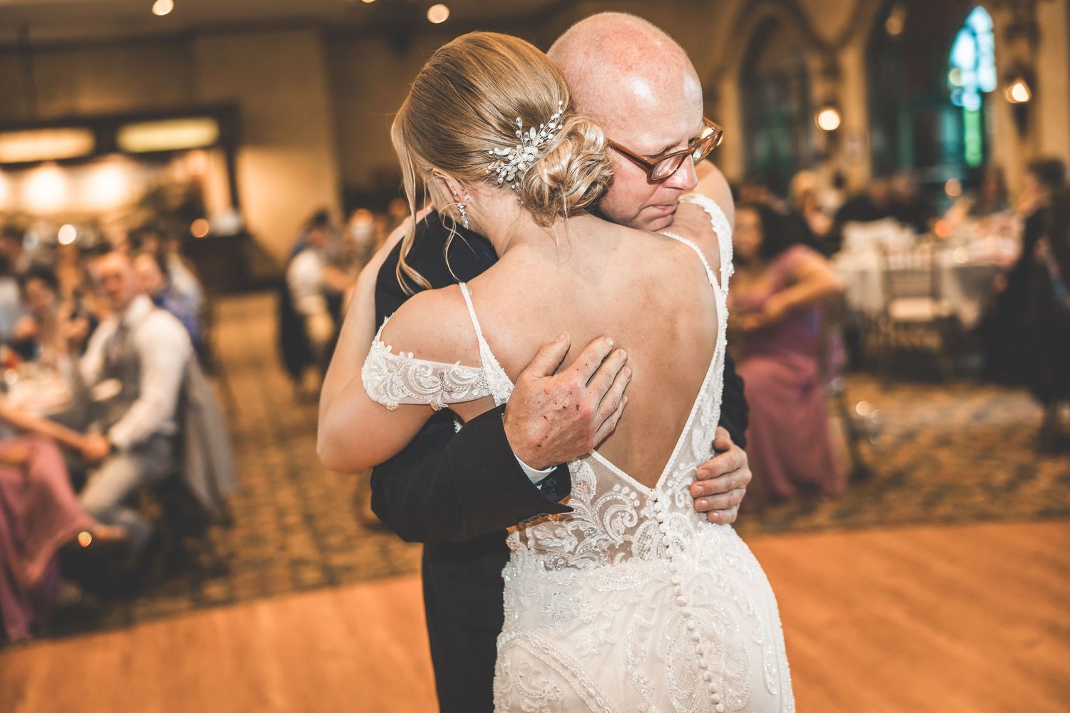 Intimate dance moment captured at an elegant wedding reception with warm lighting.