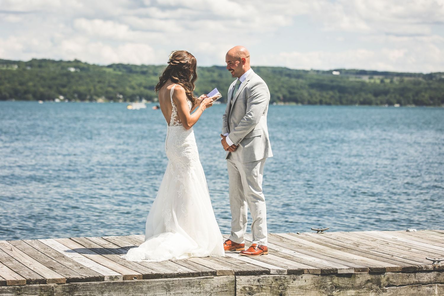 A couple in wedding attire shares an intimate conversation on a dock by the lake.