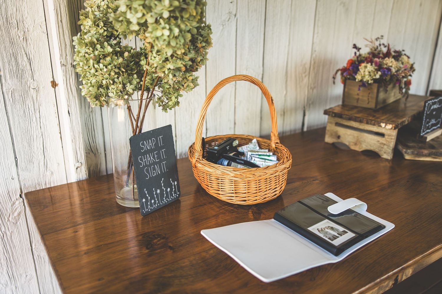 Rustic wooden table with vintage decor, baskets and greenery arrangements.