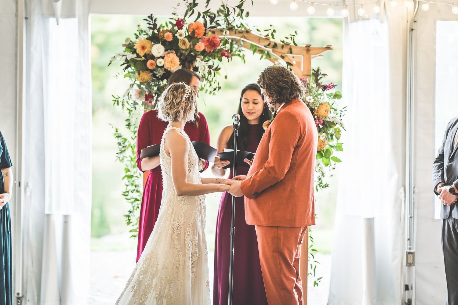 Wedding ceremony venue decorated with peach floral arrangements and hanging greenery.