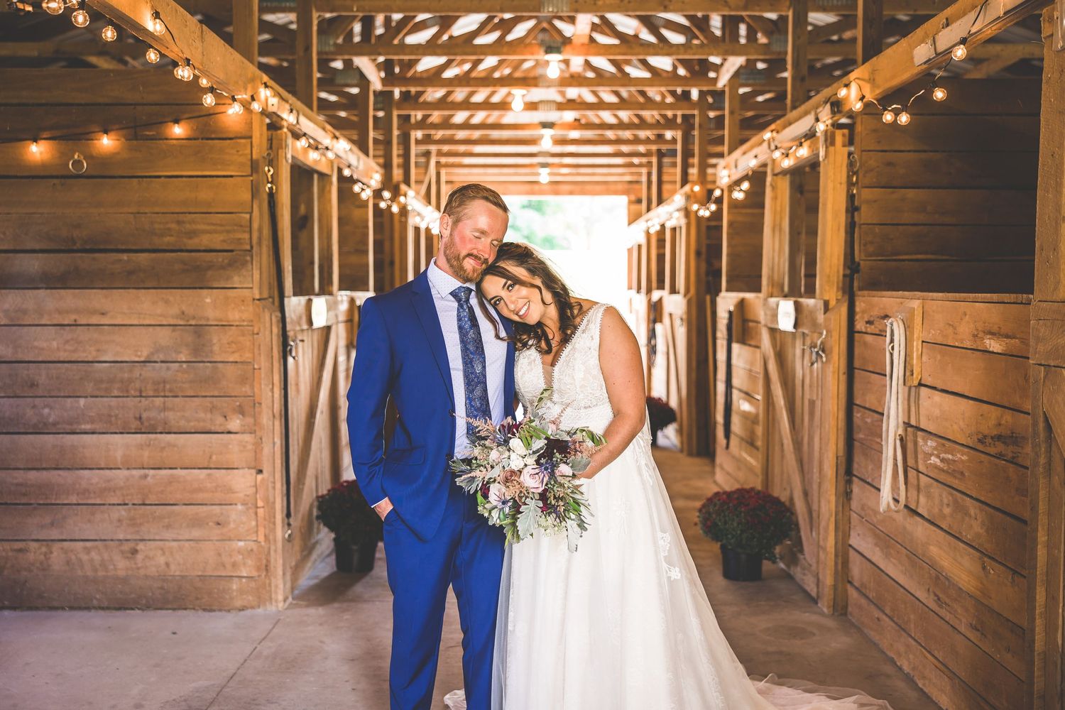 Rustic barn wedding venue decorated with string lights and wooden beams creating romantic atmosphere.