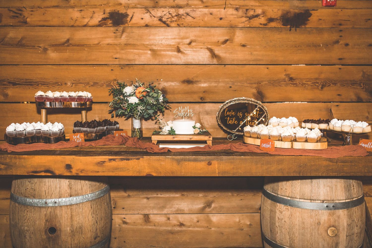 Rustic wooden barn interior with wine barrels and wedding decorations on display.