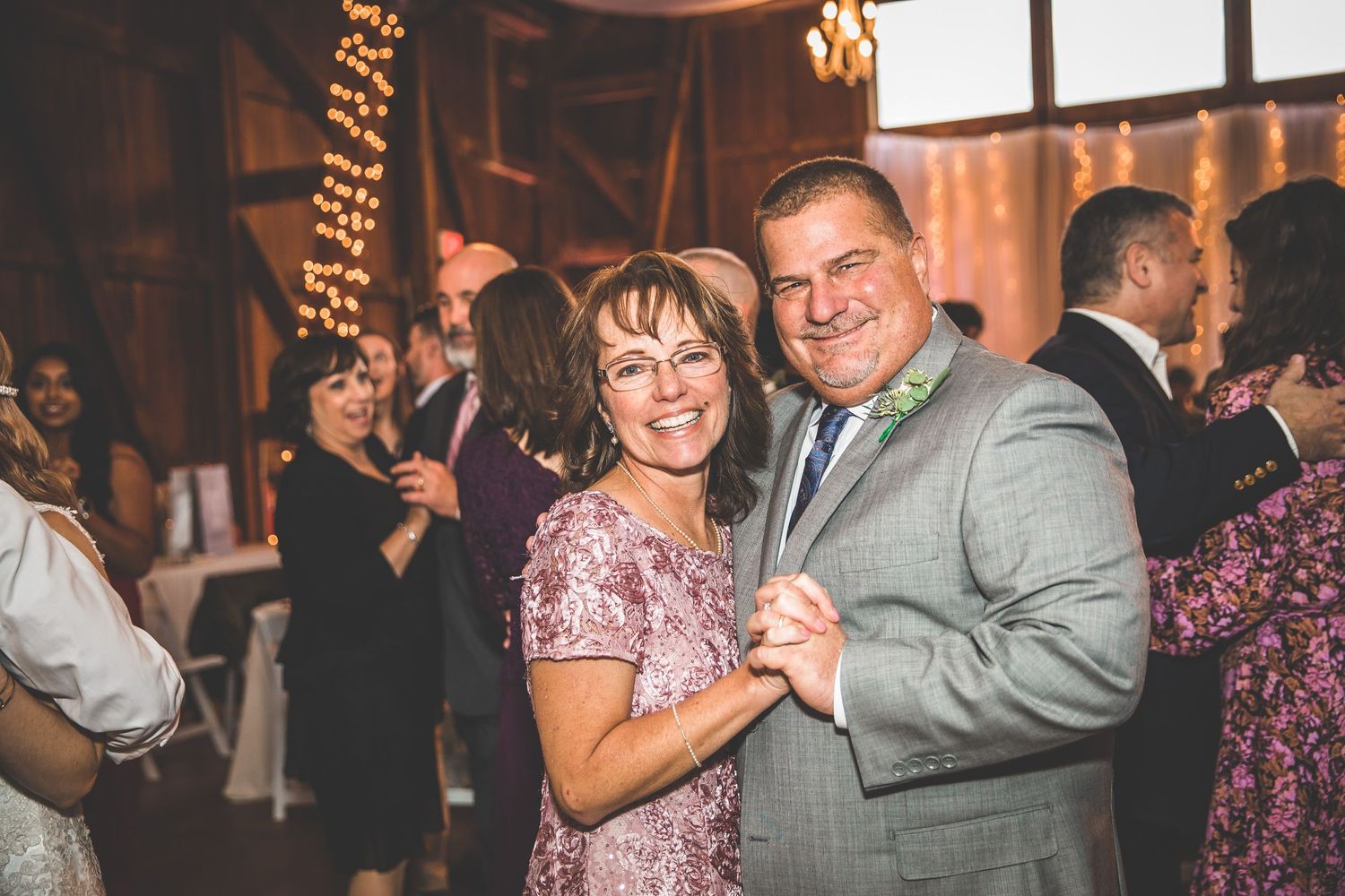 Wedding guests dancing and celebrating during reception in rustic venue.