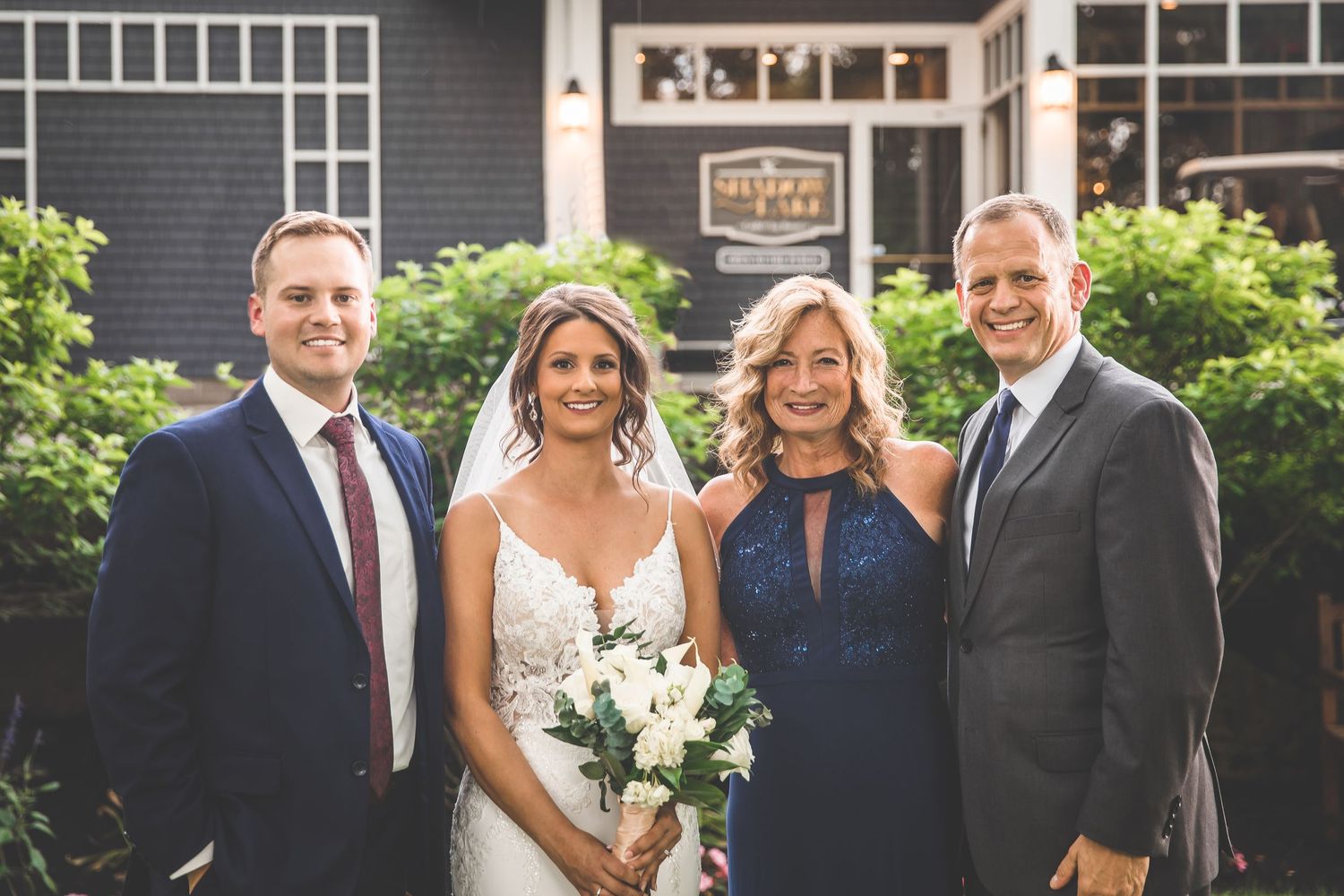 Wedding party members gather for formal photos outside charcoal colored venue.