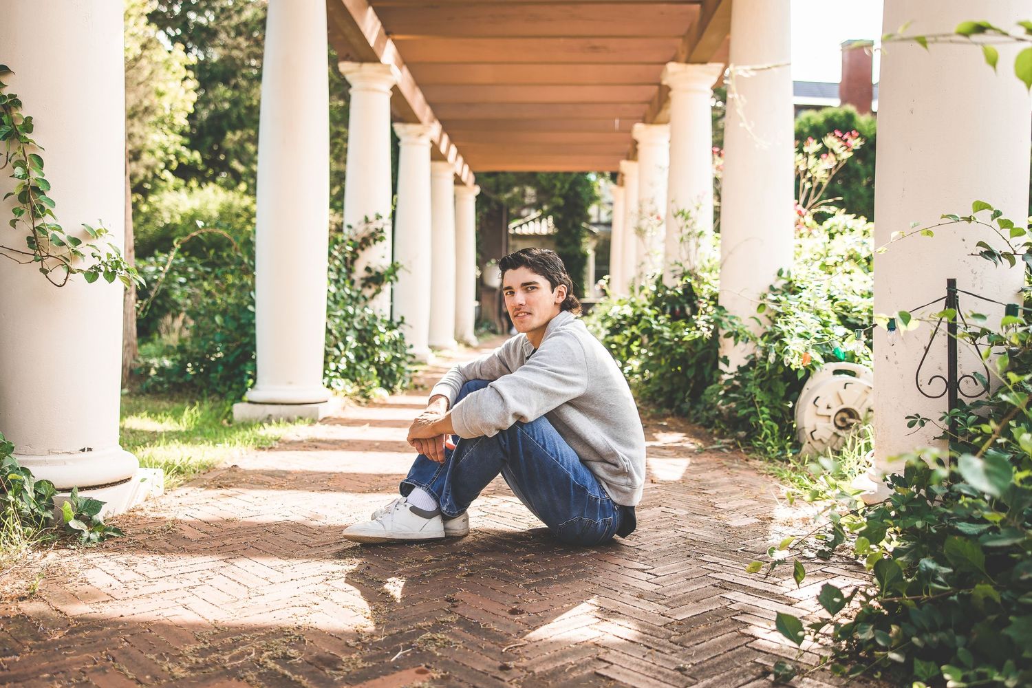 Elegant architectural engagement session under a covered colonnade with white pillars.
