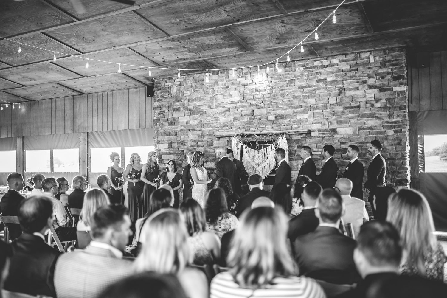 Wide angle black and white shot of wedding ceremony with seated guests.
