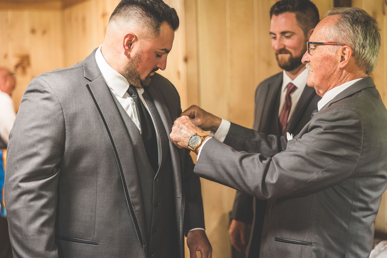 Formal gathering of suited men assisting with wedding preparations.