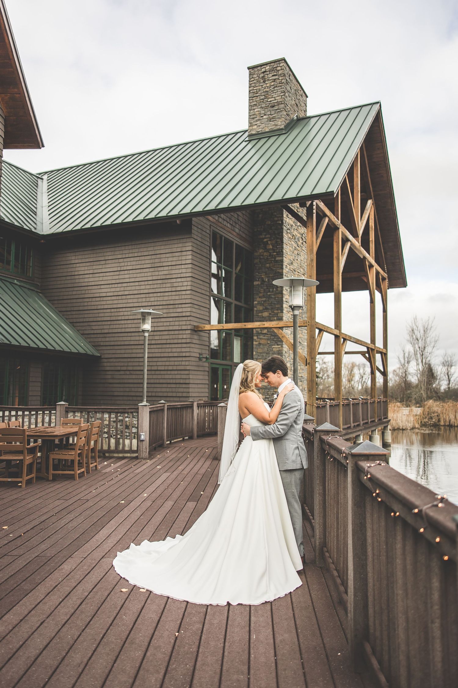 Romantic wedding moment captured on lodge deck with rustic wood and stone architecture.
