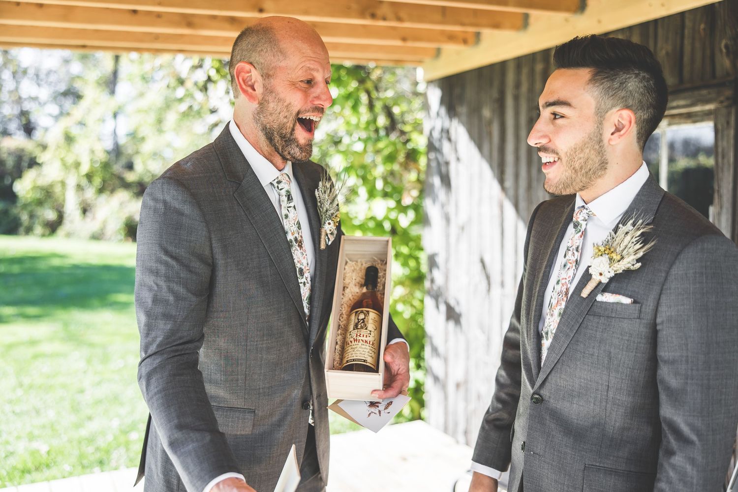 Two people in formal attire share moment with gift box on outdoor porch.
