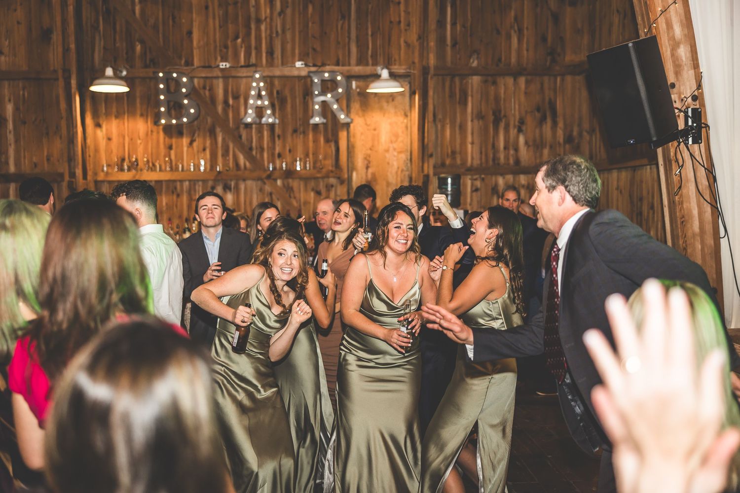 Guests dancing under string lights in rustic barn wedding venue.