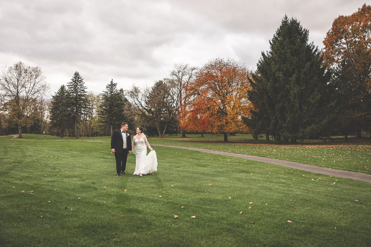 Wide landscape shots of a wedding couple in a spacious autumn park setting.