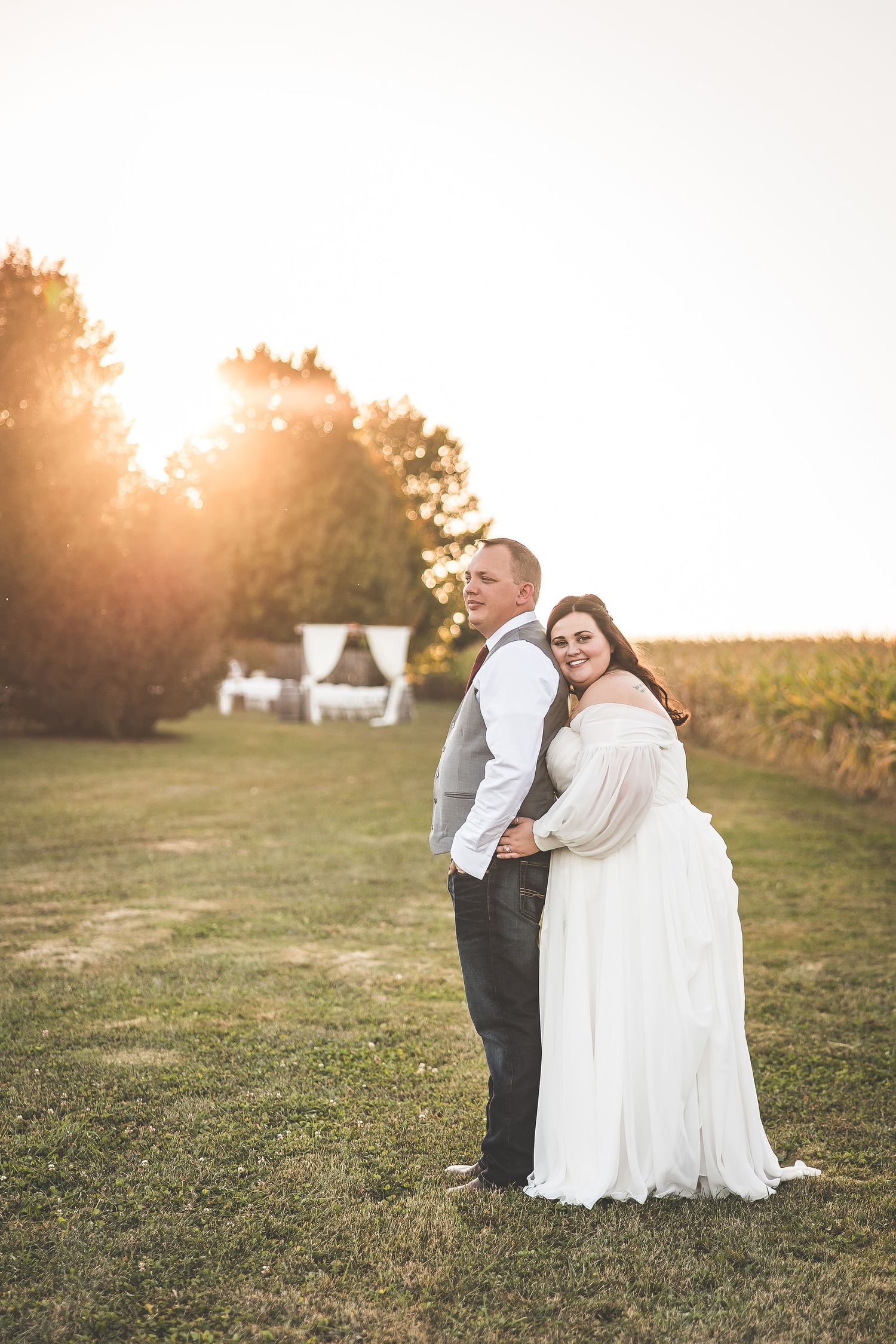 A couple shares intimate moments during their sunset wedding photoshoot in a rural setting.