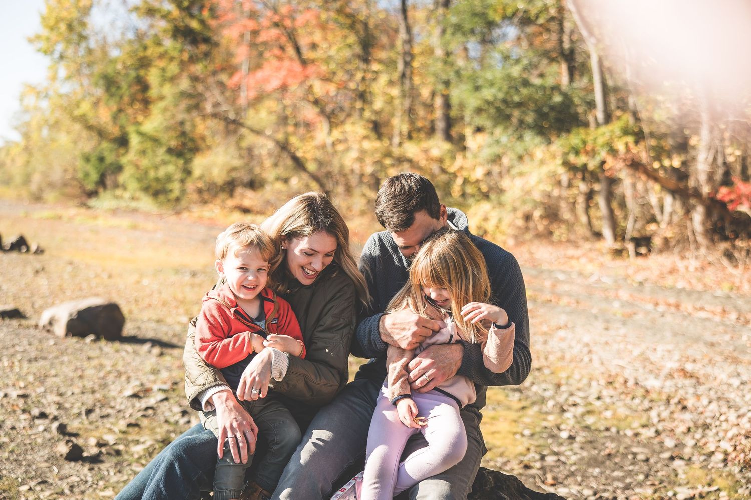 A loving family cuddles together on the ground during a fall photoshoot.