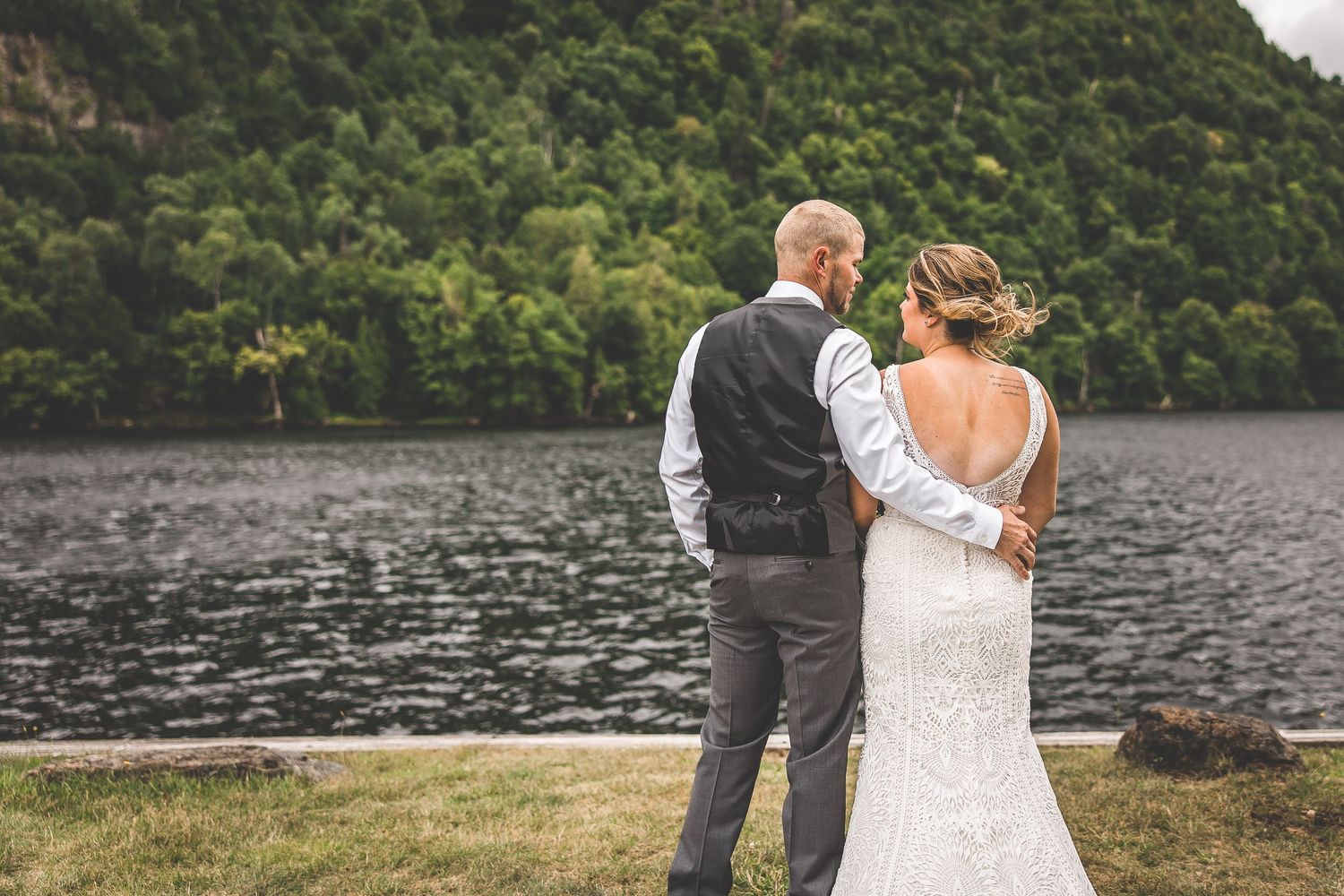 A couple shares an intimate moment while overlooking a peaceful mountain lake.