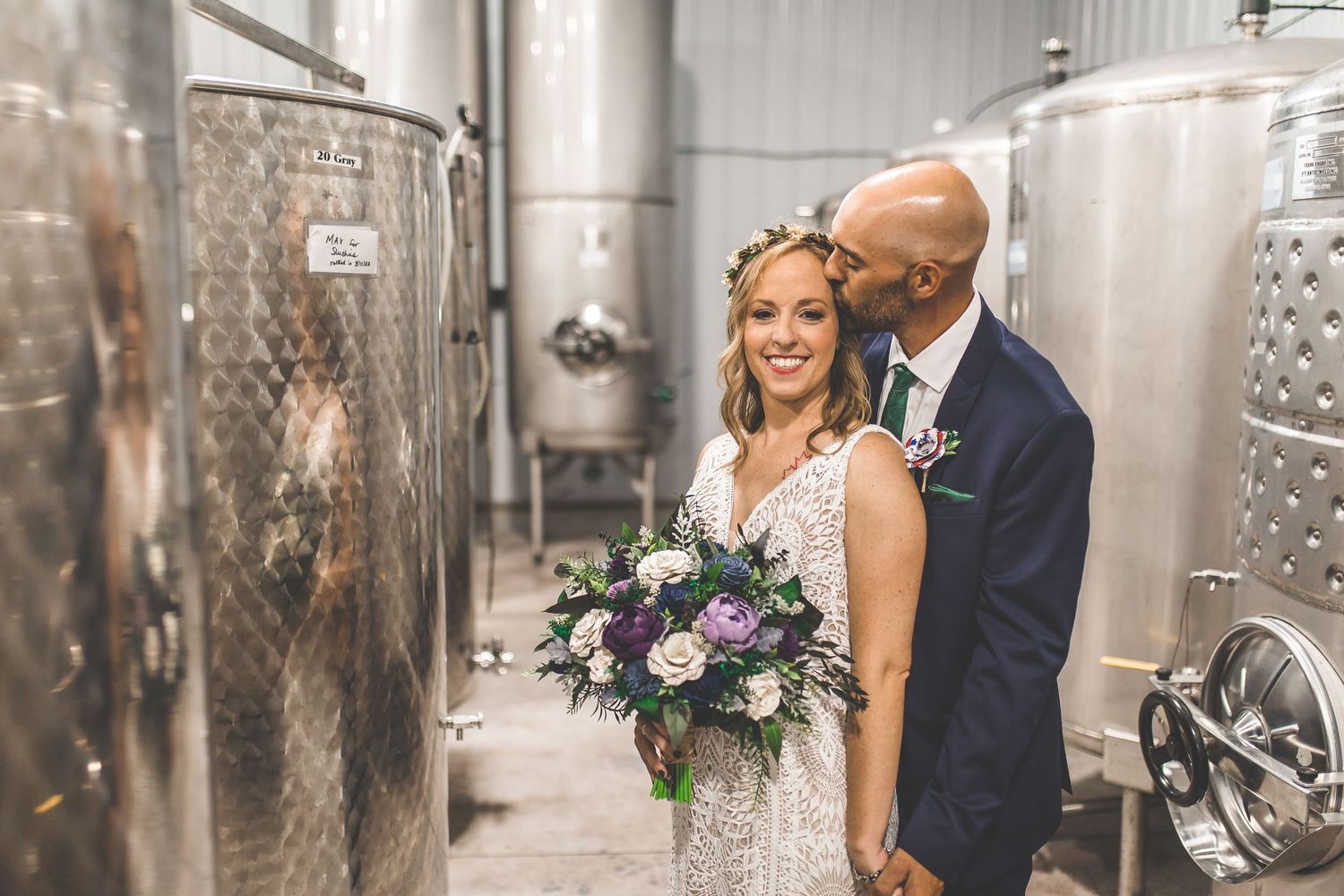 Candid wedding photography moments captured between rows of wine tanks.