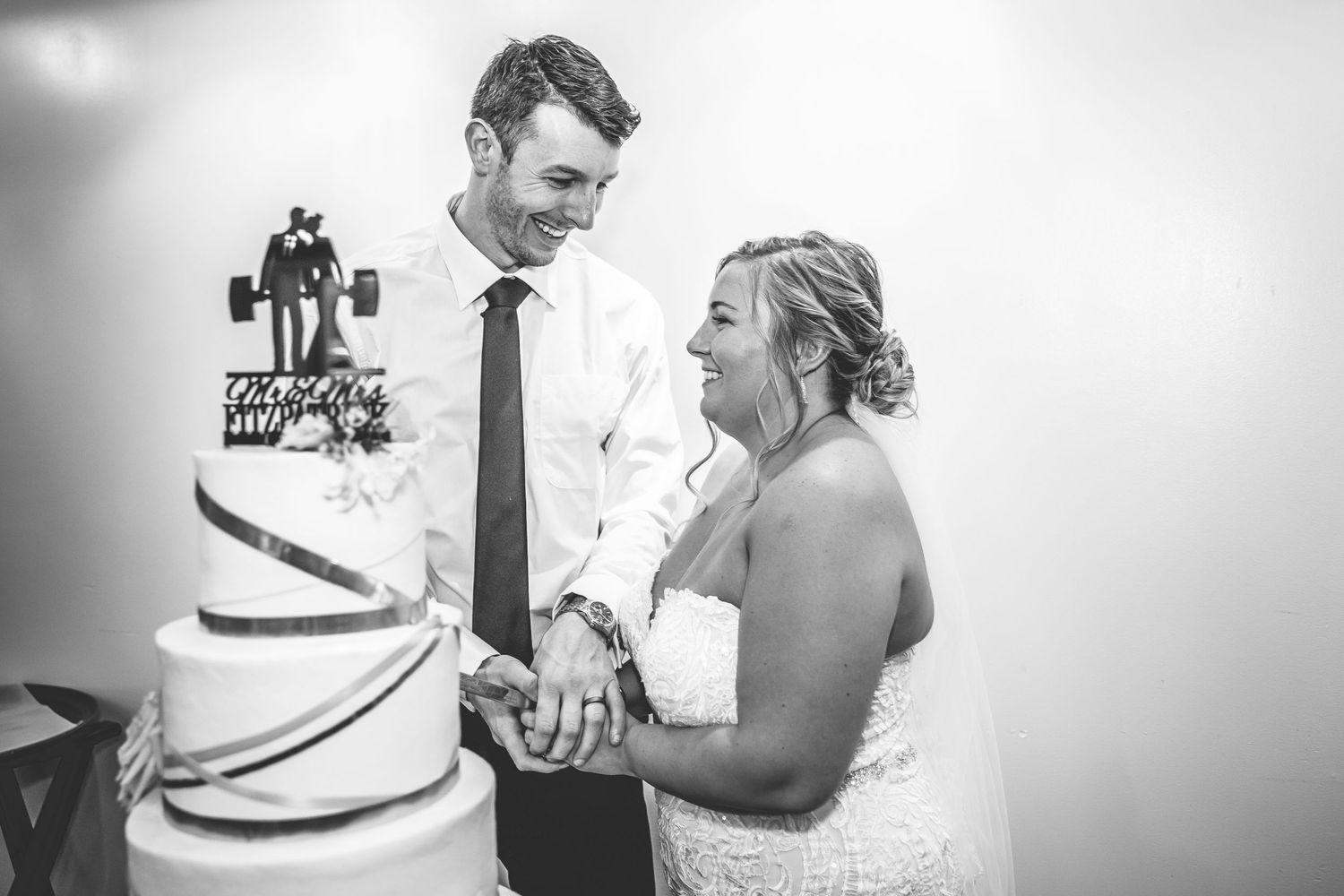 Black and white photo of wedding cake smashing moment at reception.