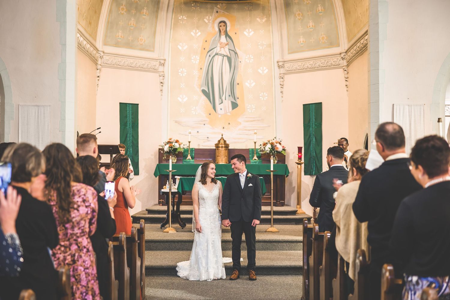 Church interior with white walls and arched ceiling during a wedding ceremony.