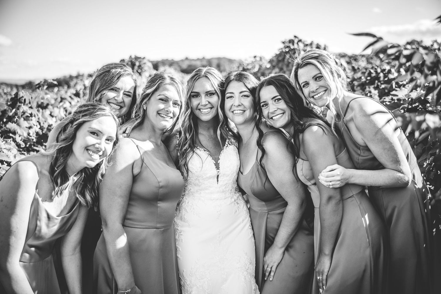 Black and white portrait of bridal party sharing laughs and embraces during wedding photoshoot.