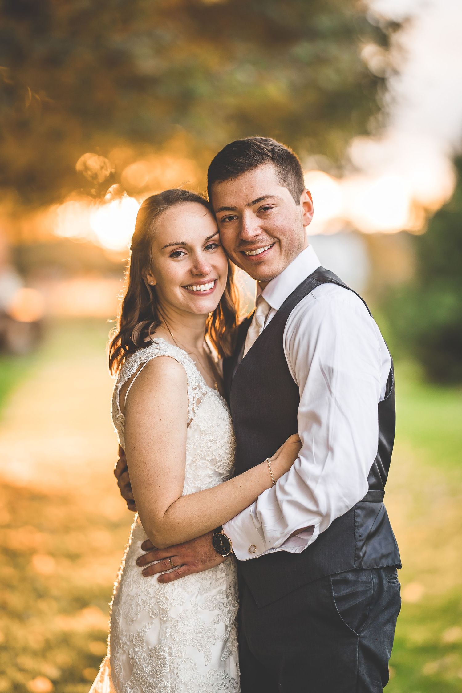 Joyful wedding portrait with warm autumn sunset glow in background.