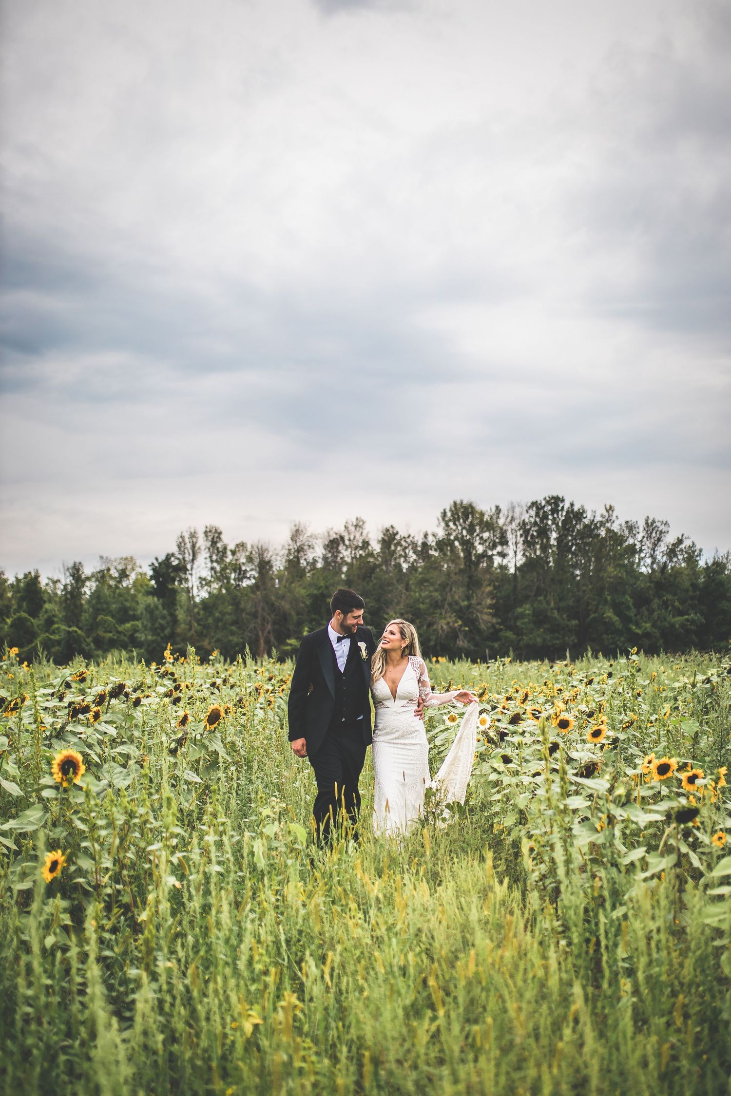 Wedding party poses in a beautiful sunflower field under cloudy skies.