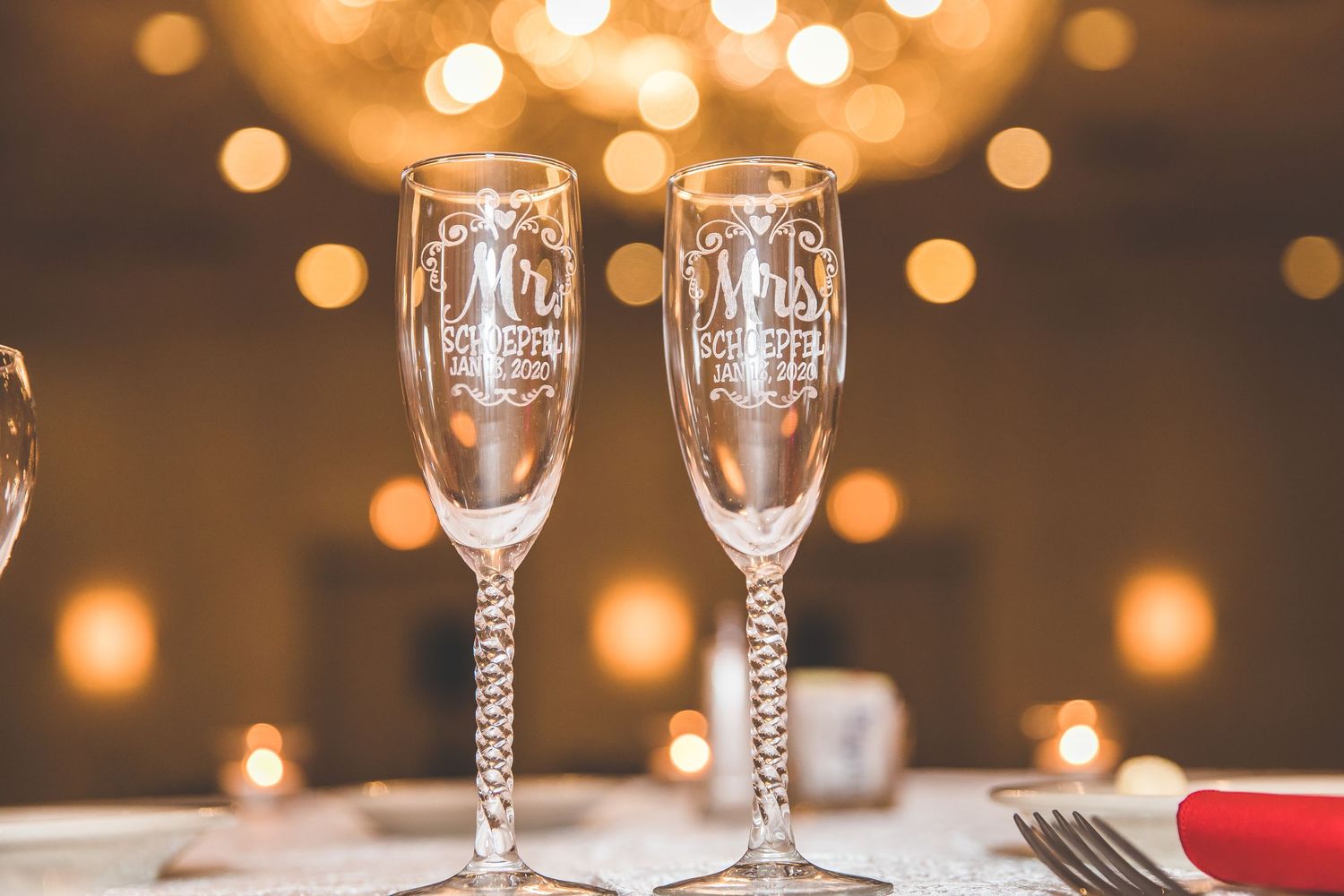 Elegant wedding champagne flutes with twisted stems displayed against warm bokeh lighting.