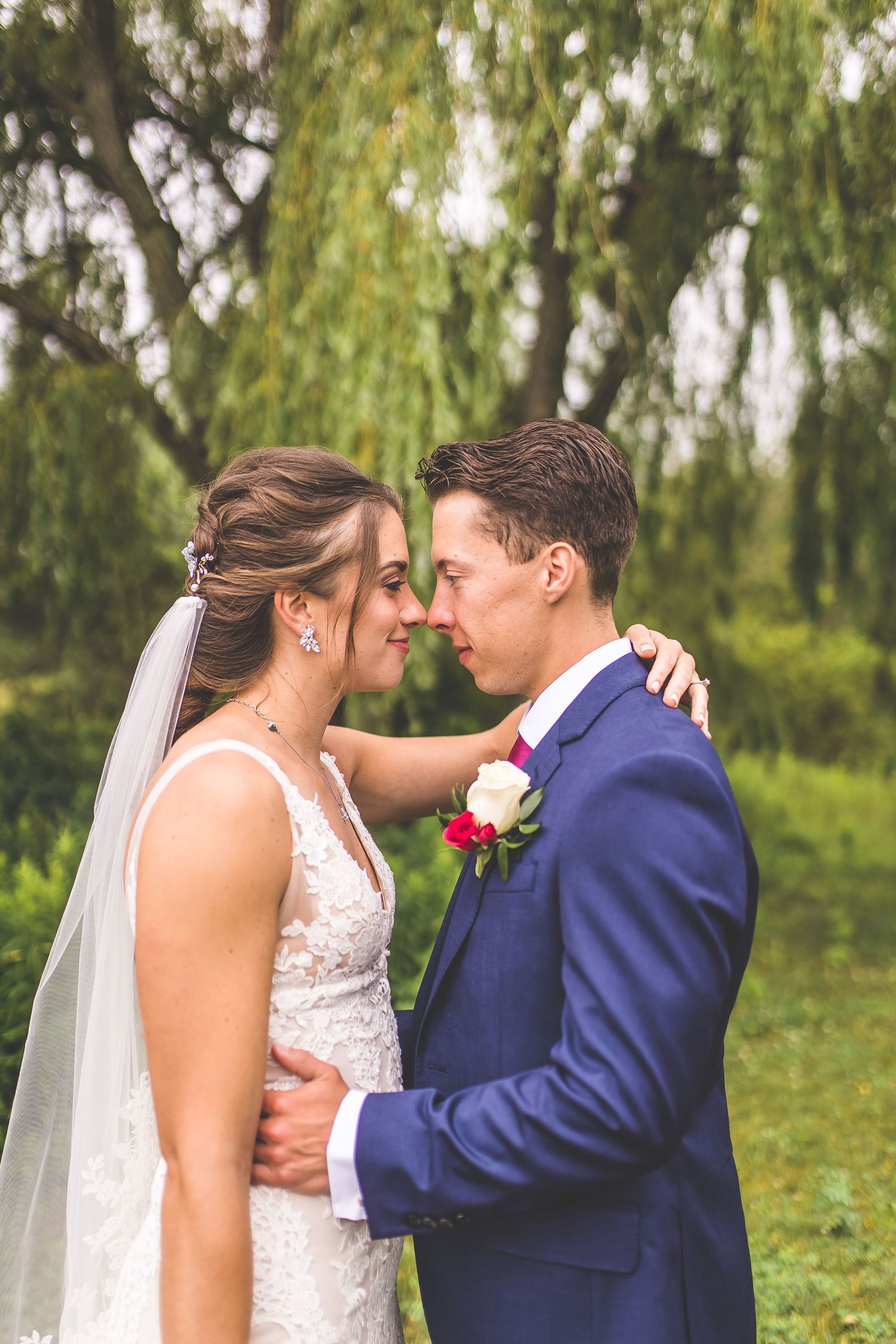 Intimate wedding portraits showing tender moments between newlyweds under a willow tree.