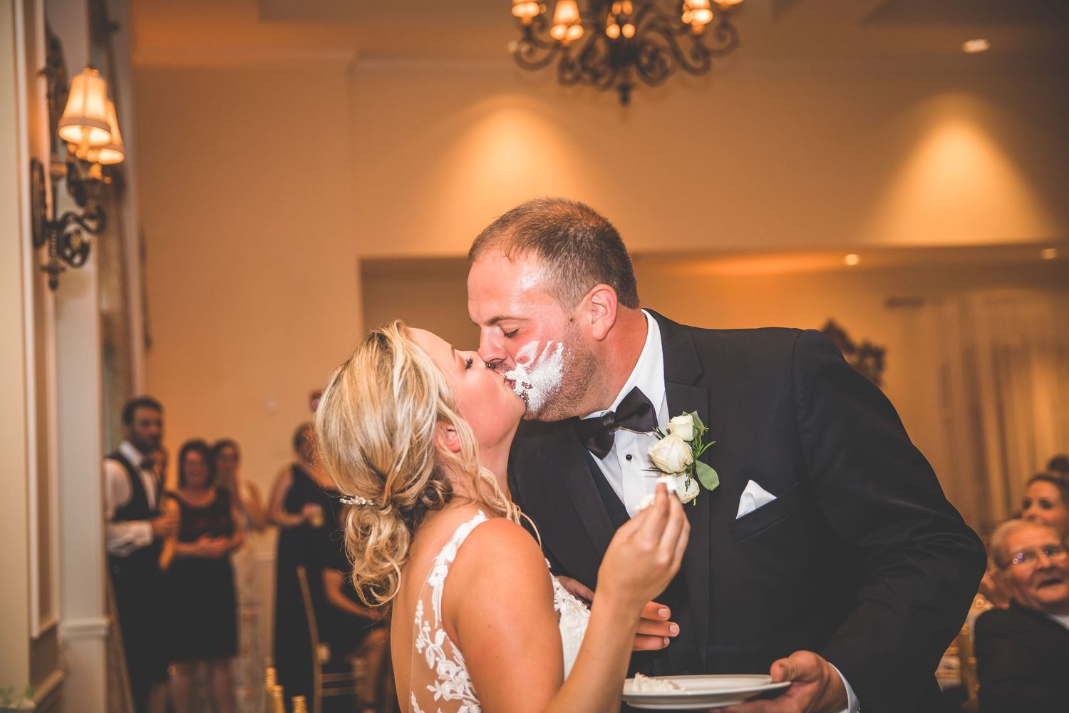 Candid reactions during cake cutting ceremony at an elegant indoor wedding reception.