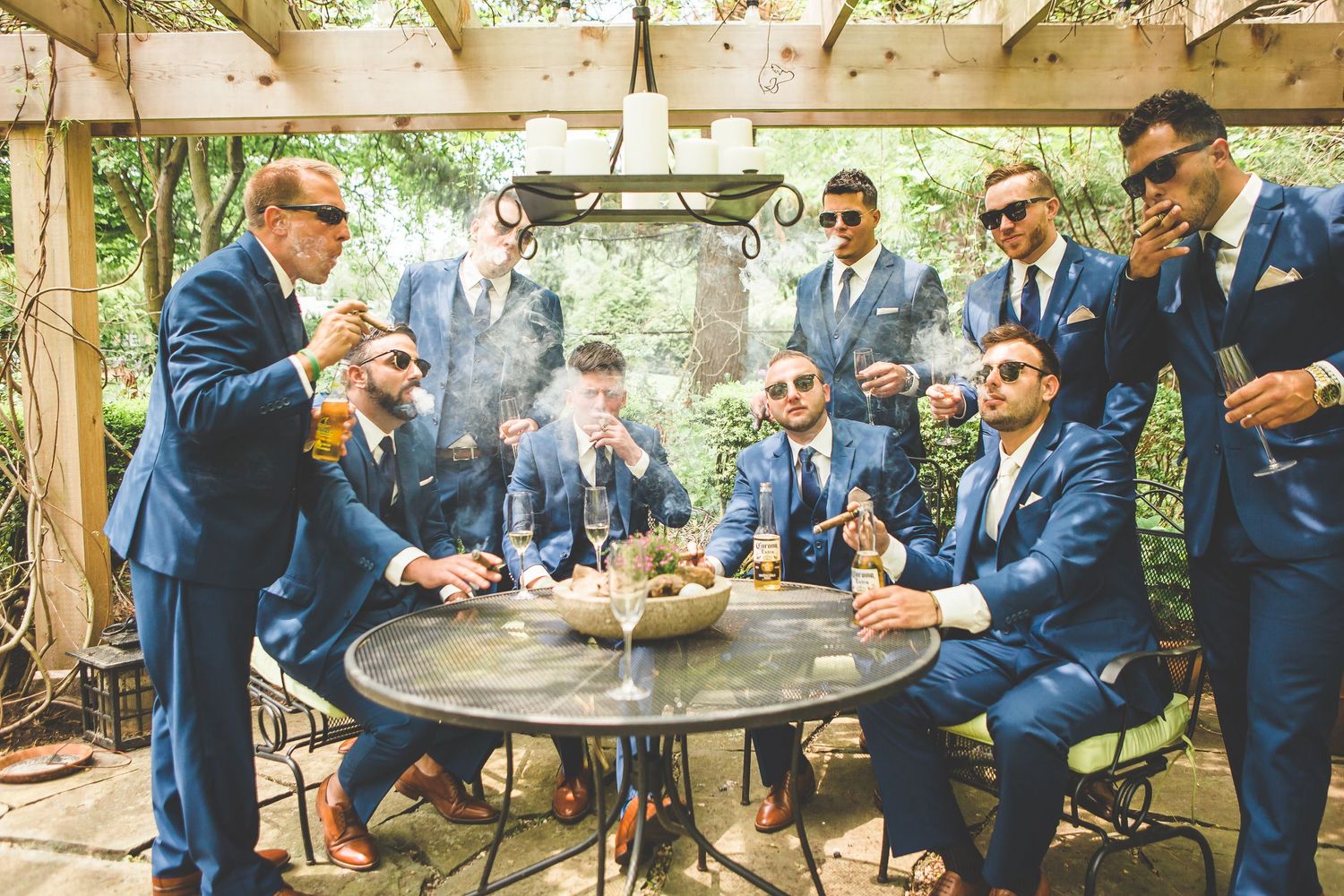Wedding party in navy suits gathered outdoors for casual group photos.