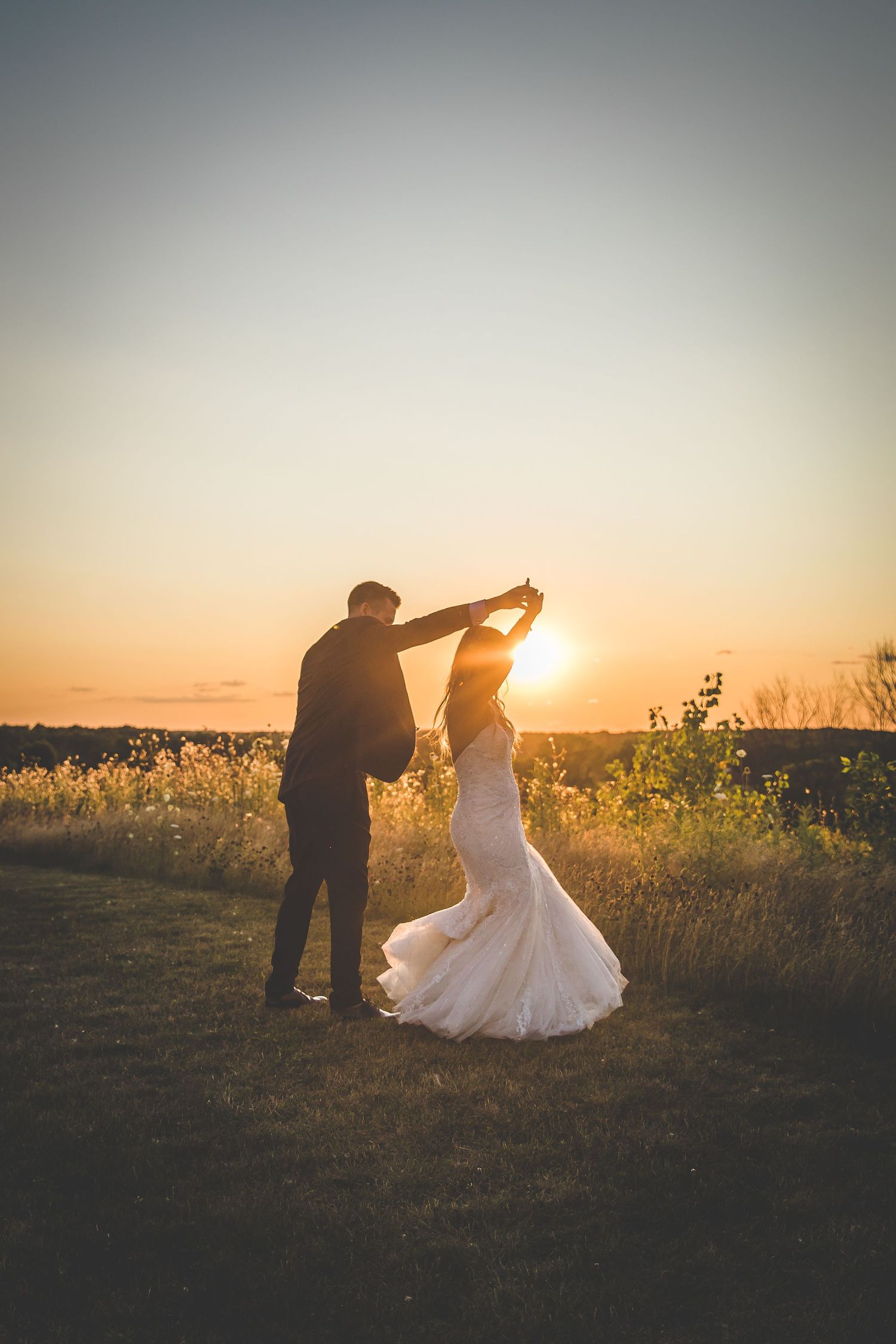 Romantic sunset silhouettes of a couple dancing in a field with golden light.