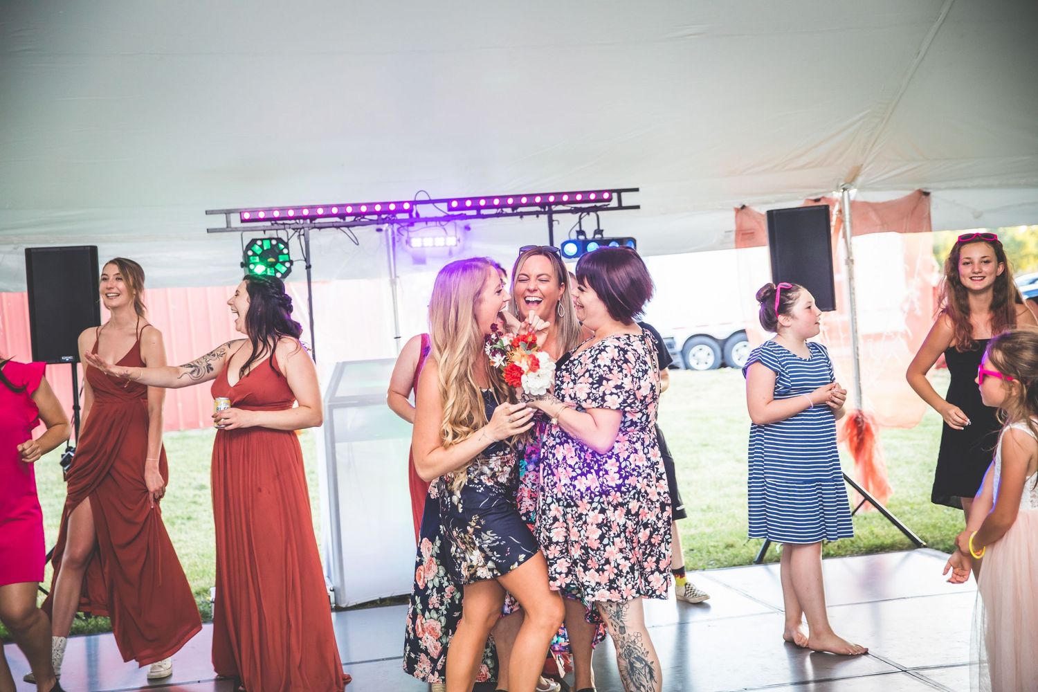 Wedding reception dance floor filled with guests under purple lighting.