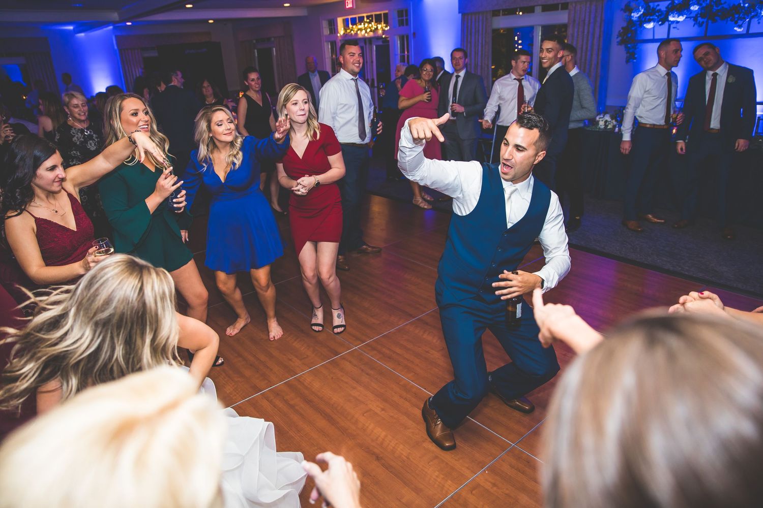 Wedding reception dance floor with blue uplighting and guests dancing.