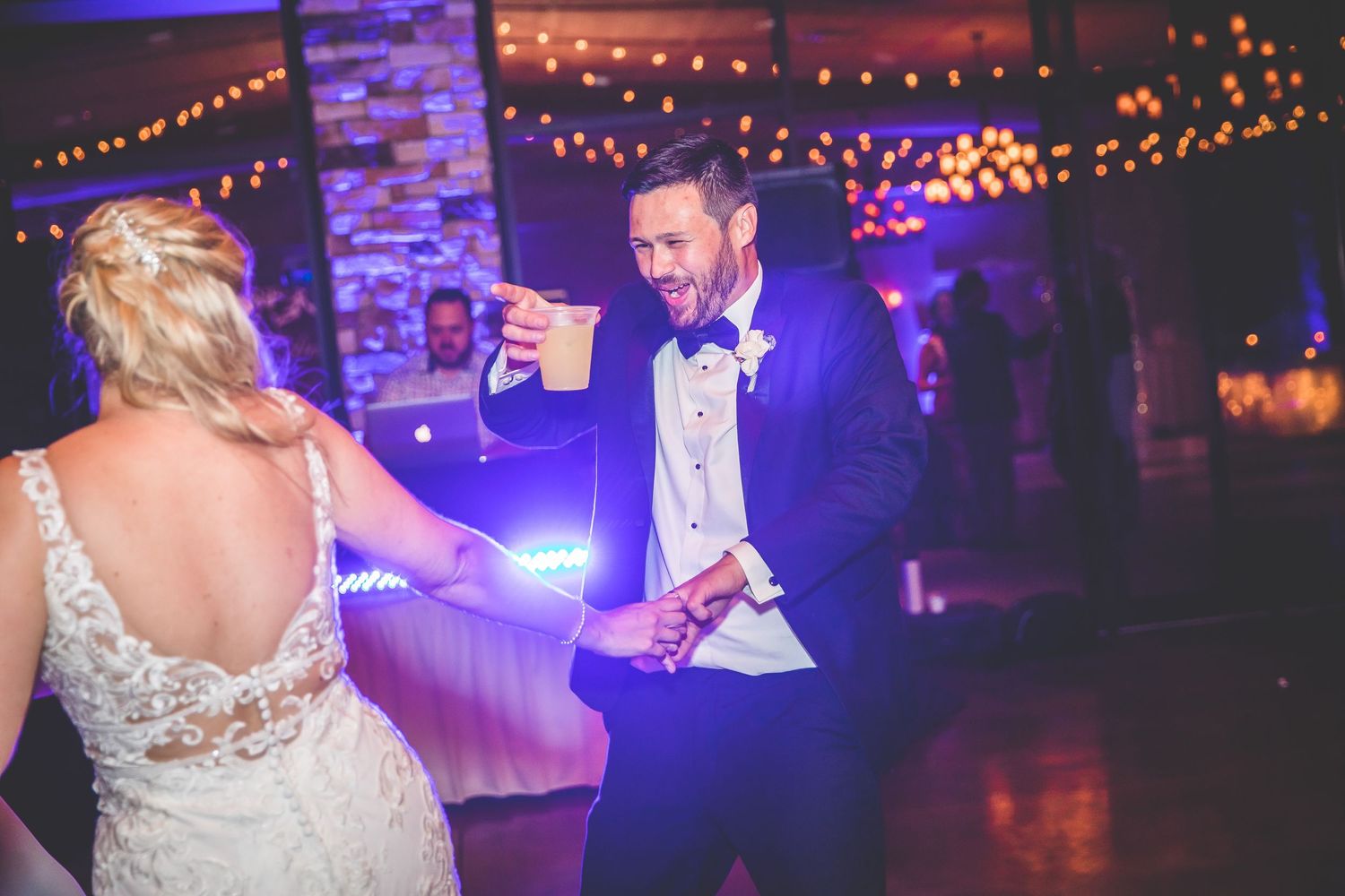 Wedding reception venue with purple mood lighting and string lights creating a romantic atmosphere.