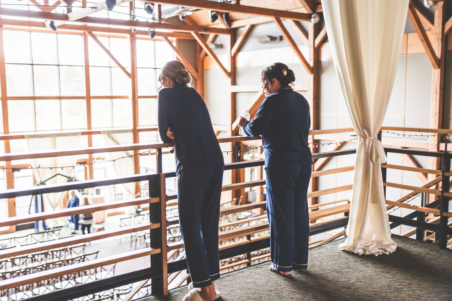 Panoramic view of a rustic venue interior with wooden beams and white drapes.