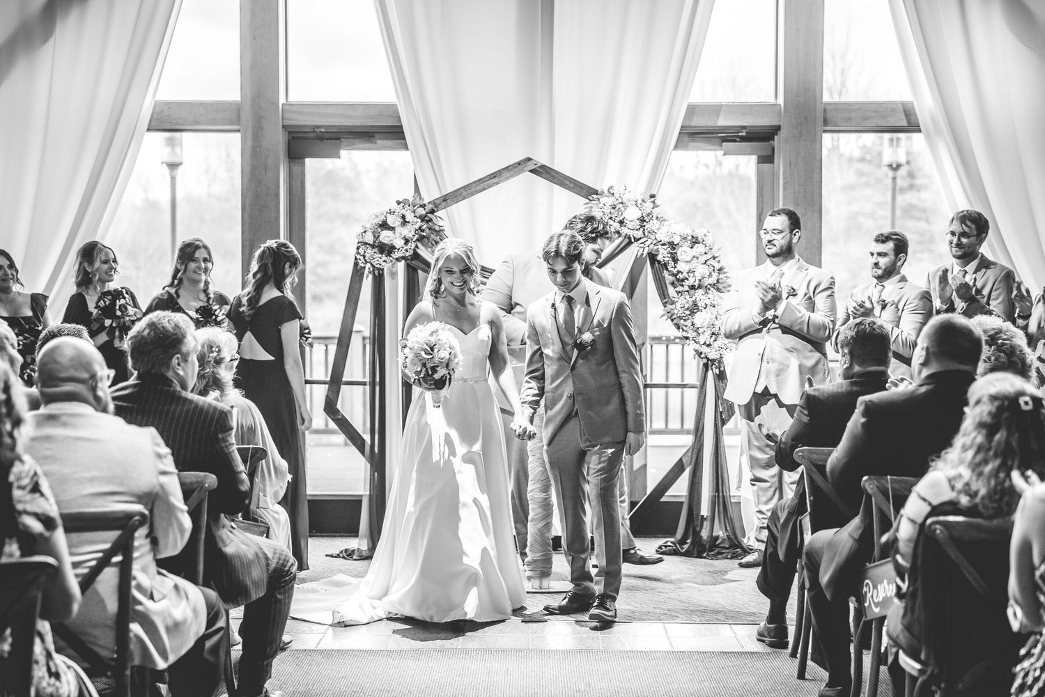 Wide-angle shots of a wedding ceremony showing guests and decor in black and white.