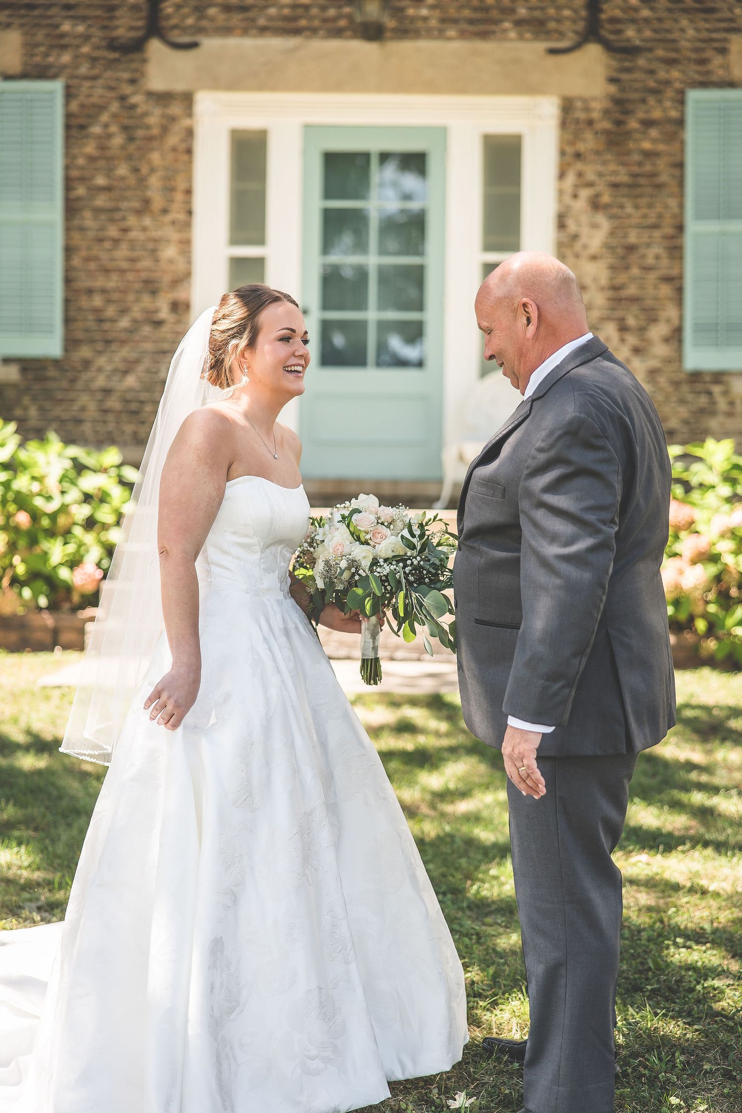Sweet first look moment between the bride and a loved one in front of a historic building.