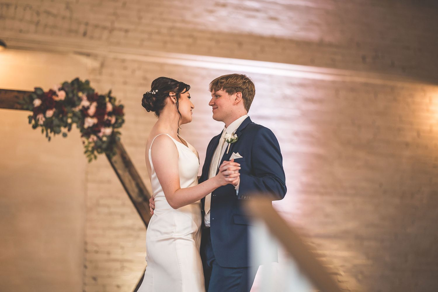Couple performs their first dance in a rustic-modern wedding venue.