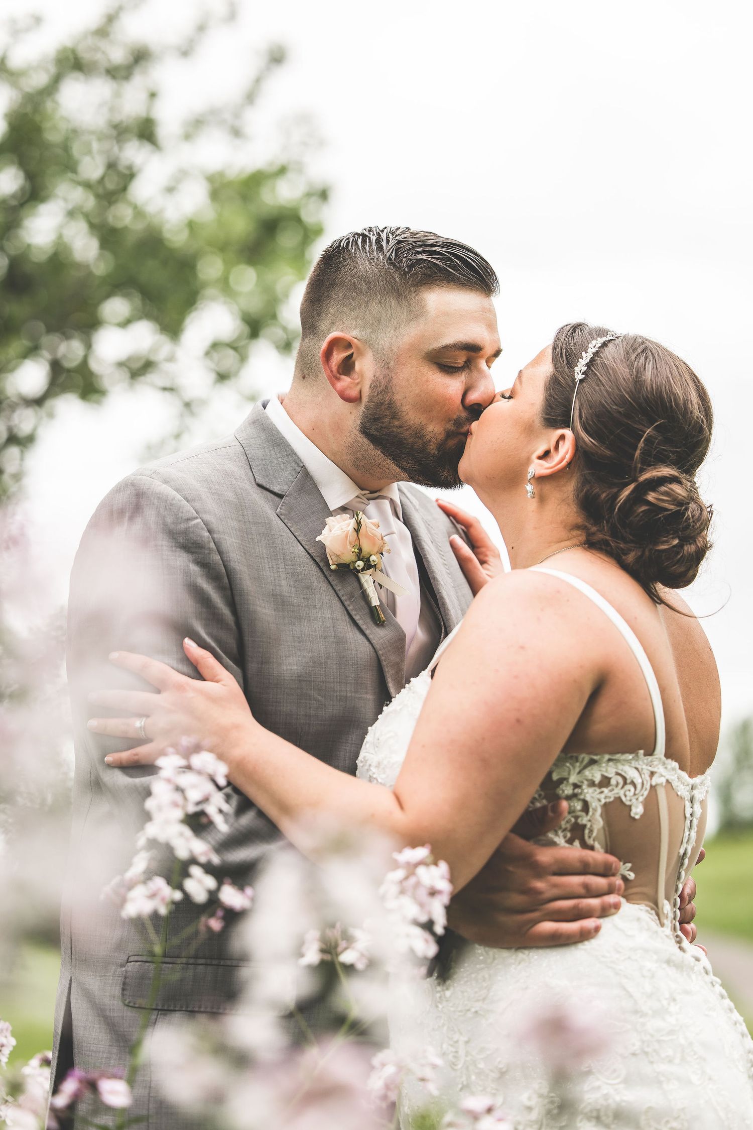 A romantic kiss captured among blooming flowers with soft focus and dreamy lighting.