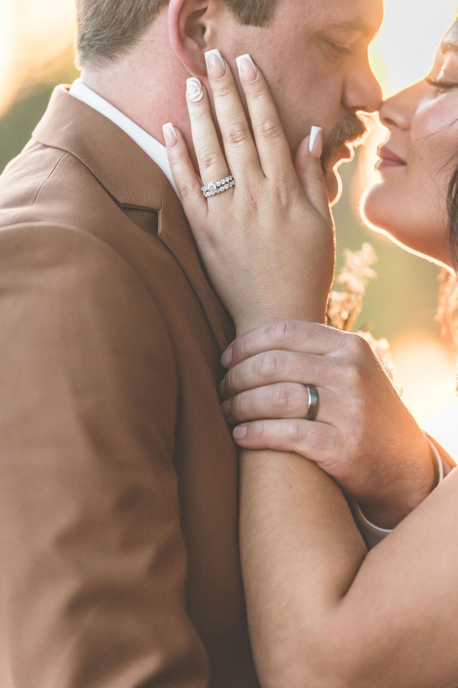 Intimate close-up wedding portrait with golden sunlight and delicate ring details.