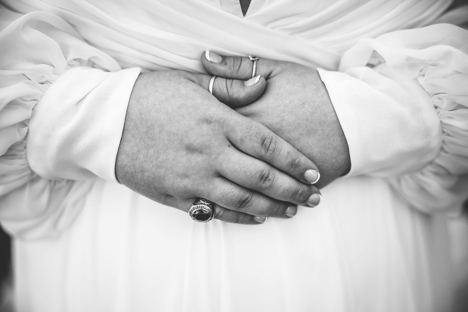 Black and white detail shots of hands and wedding dress fabric.