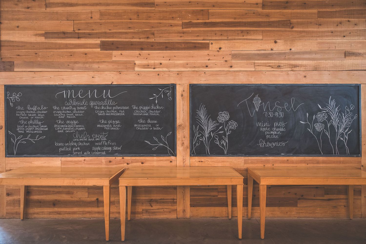 Rustic wooden wall with decorative chalkboard signs and menu displays.