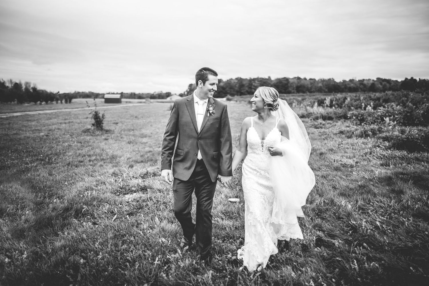 Black and white wedding portraits capture romantic poses in a rustic outdoor landscape.