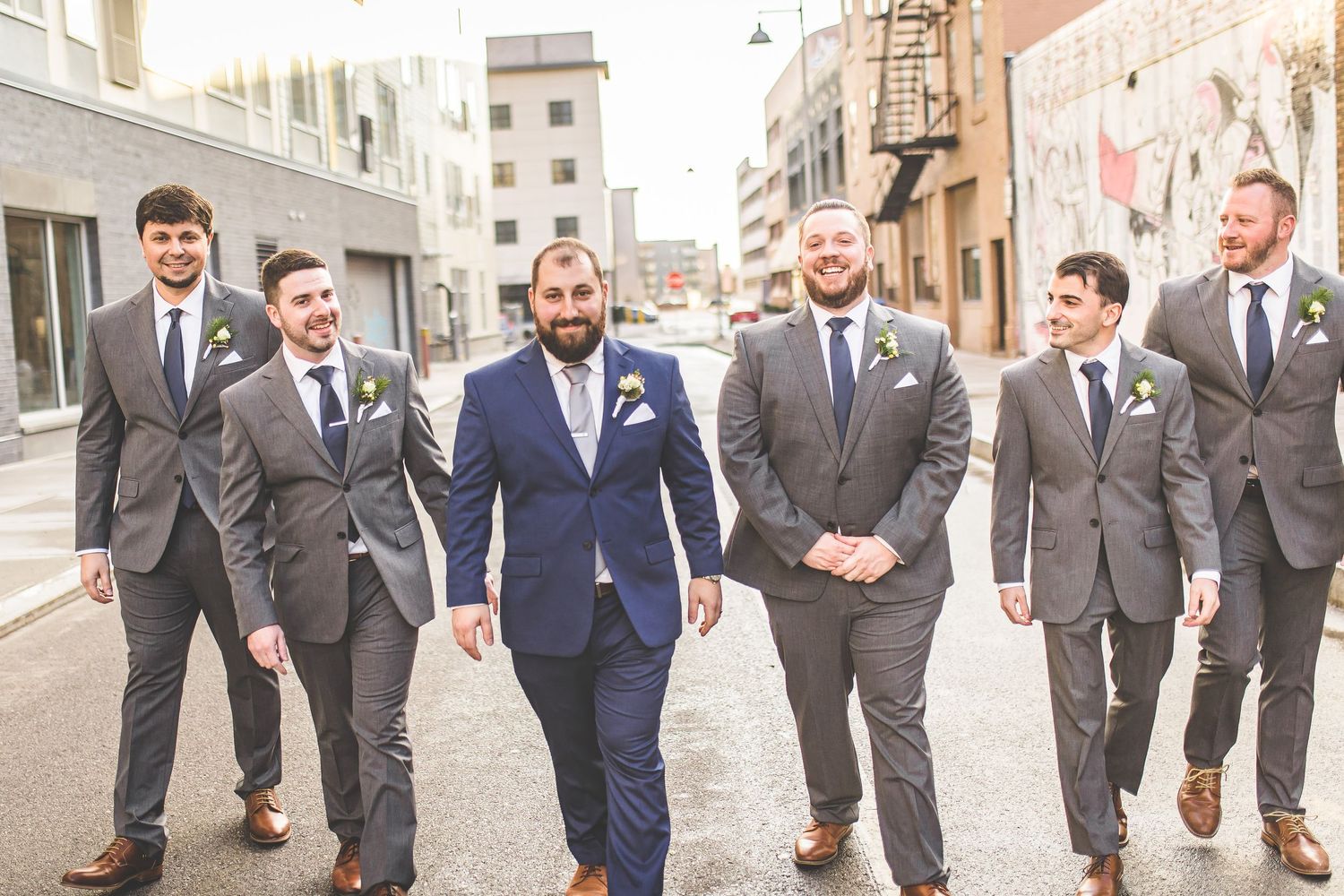 Wedding party members walk casually down urban street.